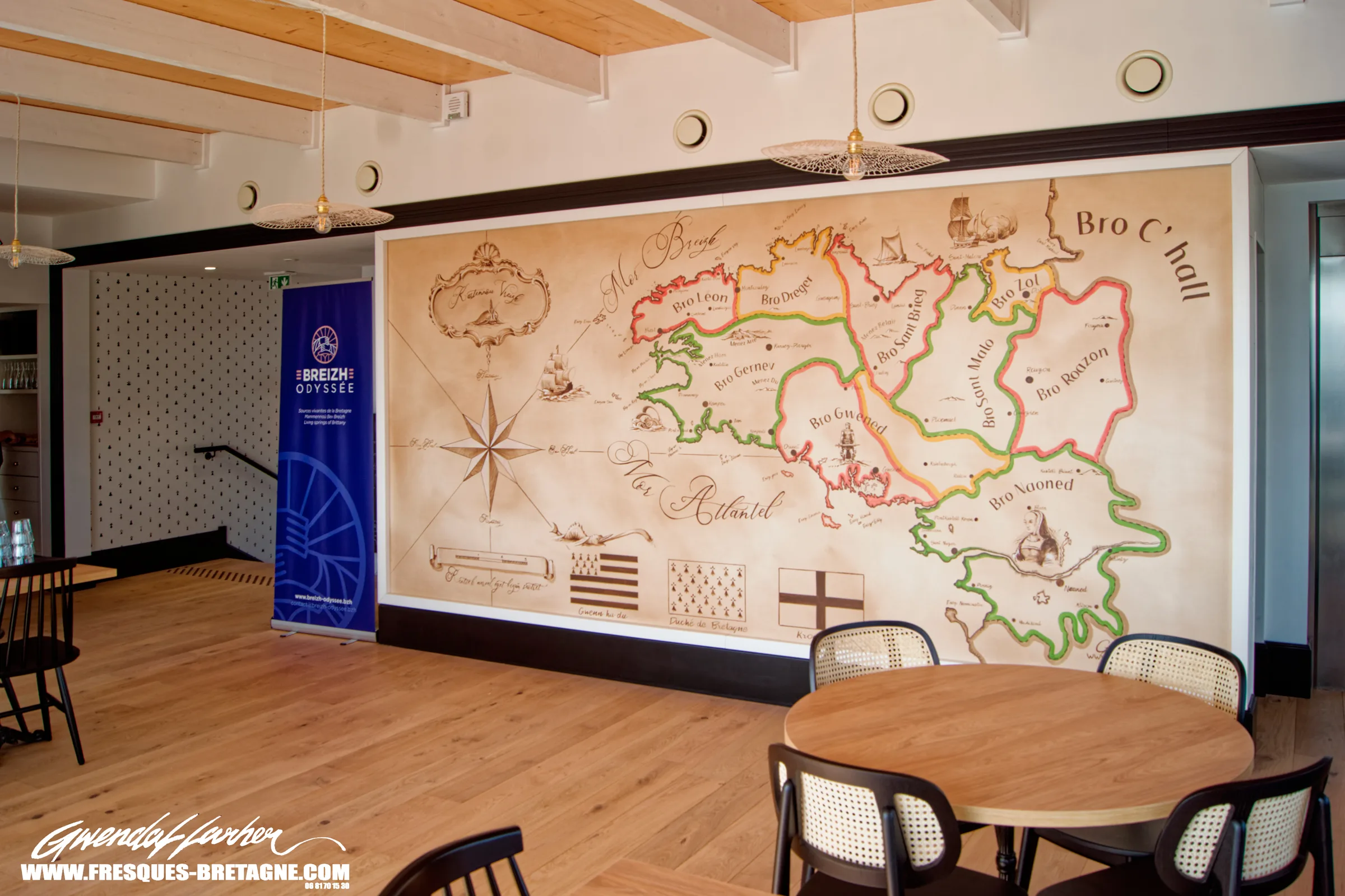 Restaurant d'un espace muséographique à Landévennec : grande carte culturelle de la Bretagne peinte sur le mur, tables rondes et parquet clair